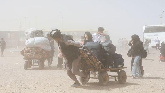 رجل يجر عربة محملة بأمتعة بعد الترحيل من إيران نحو أفغانستان