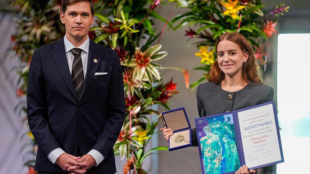 La hija de maría corina machado, ana corina sosa machado, sostiene el premio nobel de la paz. 