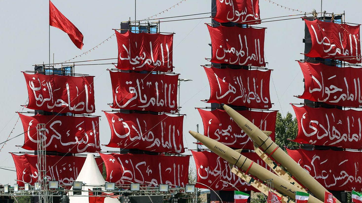 Navios com velas vermelhas e inscri&ccedil;&otilde;es em farsi, com m&iacute;sseis &agrave; frente, durante uma celebra&ccedil;&atilde;o militar no Ir&atilde;