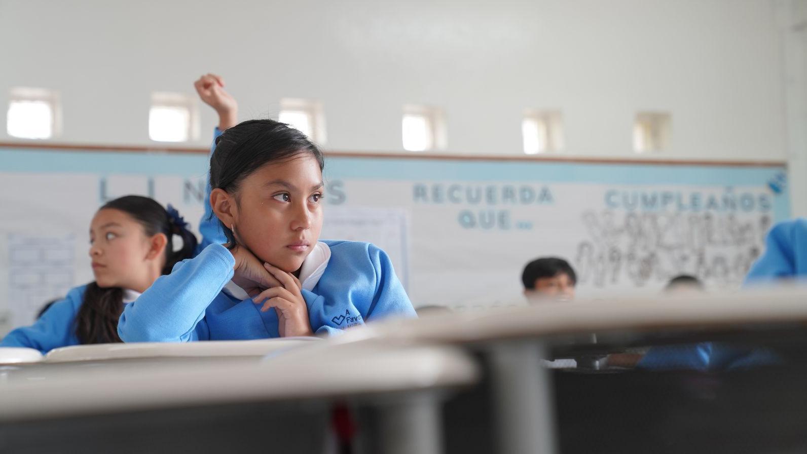 Una niña con uniforme azul en un aula de la escuela. 
