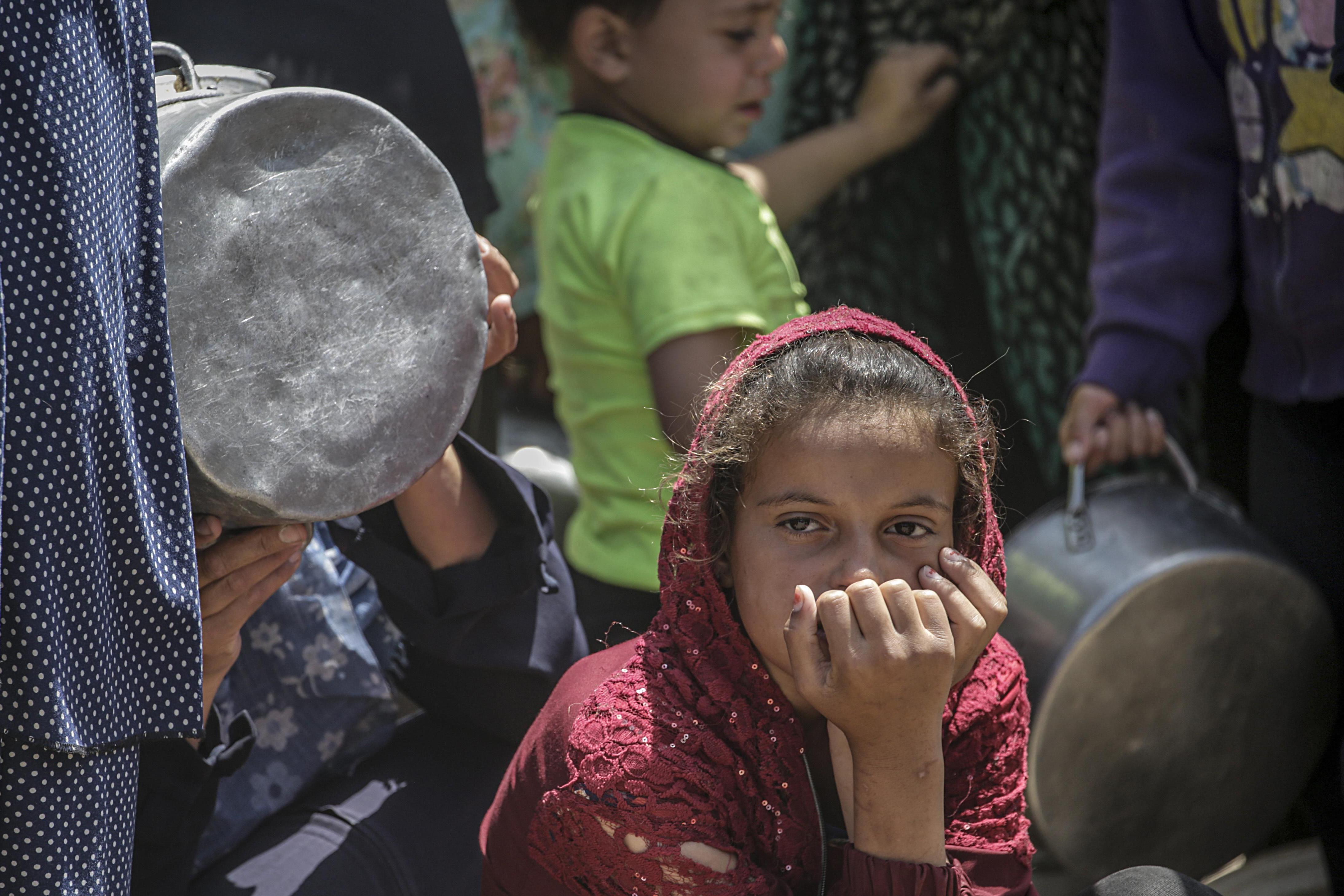 Una niña parece cansada y preocupada mientras espera recibir alimentos de una cocina benéfica en el campo de refugiados de Yabalia, en el norte de Gaza, 9 de mayo de 2025