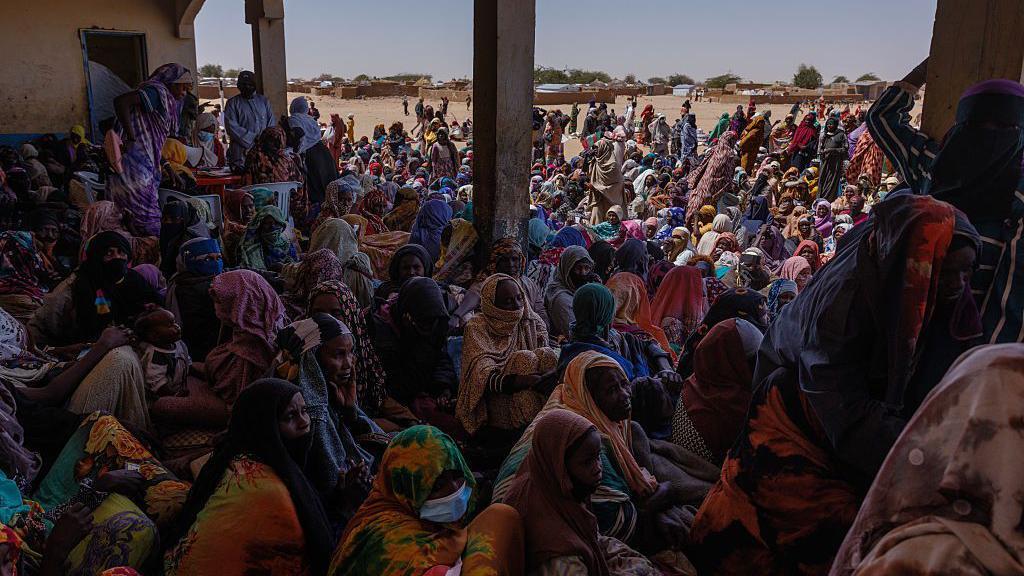 Cientos de refugiados sentados en un albergue en Chad.