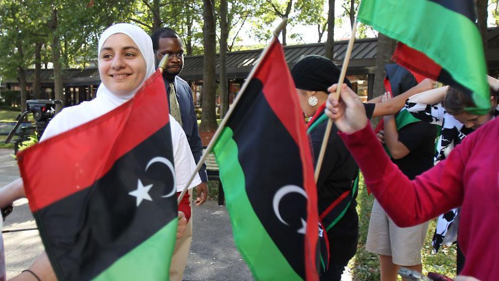 "أُغلق الباب في وجوههم ظلماً": كيف بدّد الحظر الأمريكي أحلام القادمين من دول عربية منكوبة؟ 4 أعضاء من منظمة "ليبيون من أجل الحرية" يحتفلون أمام مبنى ميكي ليلاند الفيدرالي في هيوستن عام 2011، بعد سقوط حكم معمر القذافي.