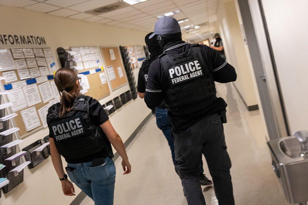 Tres agentes federales con chalecos balísticos caminan por un juzgado de Inmigración. 