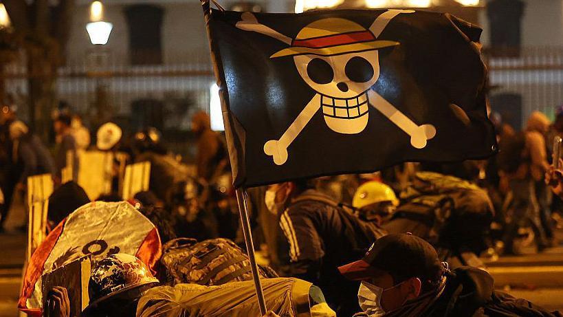 Manifestantes con una bandera de la serie de manga "One Piece" se enfrentan a la policía antidisturbios durante una protesta contra el presidente interino de Perú.
