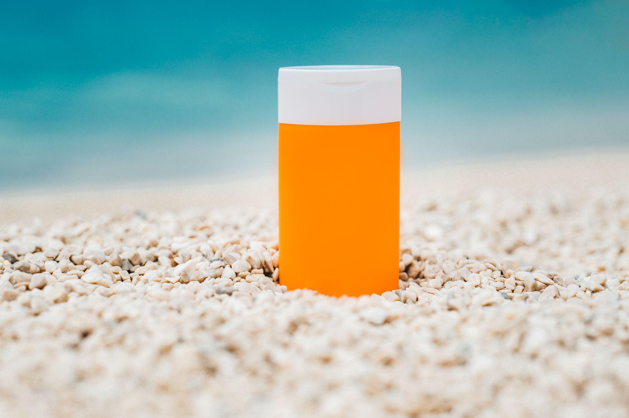 Un frasco de bloqueador solar en la arena de la playa.