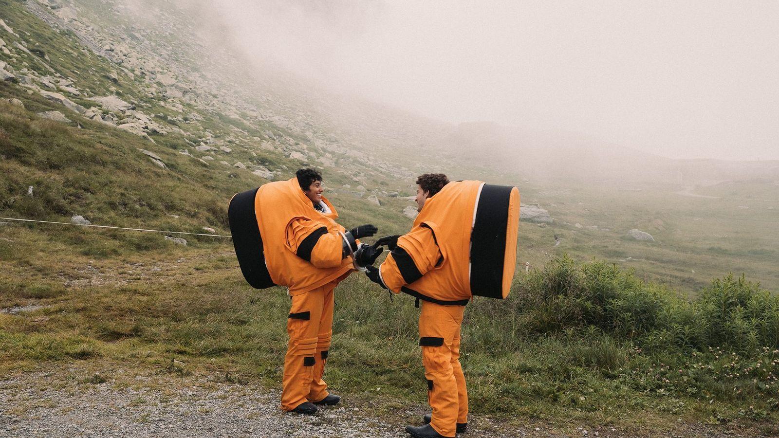 Dos personas con trajes naranjas de astronauta en los Alpes suizos. 
