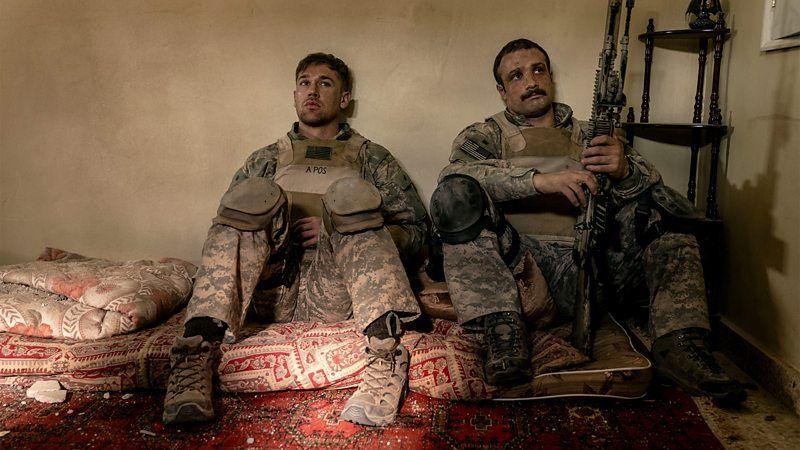Cena do filme 'Tempo de Guerra' mostra dois soldados sentados em uma cama, um deles armado
