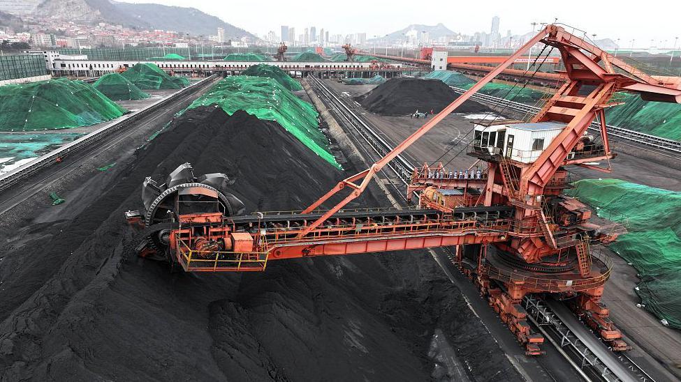 Maquinaria pesada apila carbón de reserva en un patio terminal.