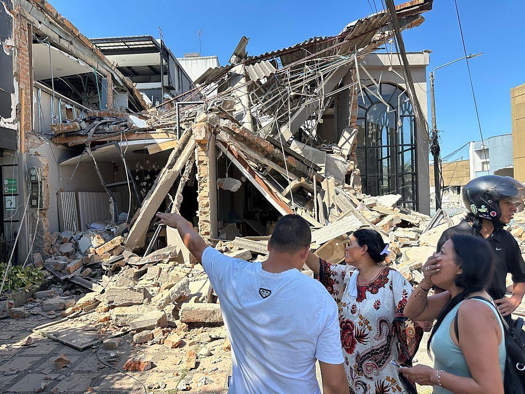Personas en una calle de Pereira miran con asombro los daños que dejó el terremoto en diferentes propiedades.