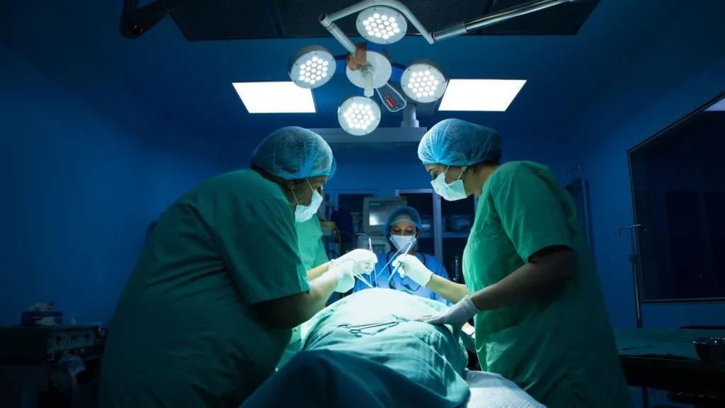 مريض اثناء عملية جراحية وحوله عدد من الفريق الطبي المعالج