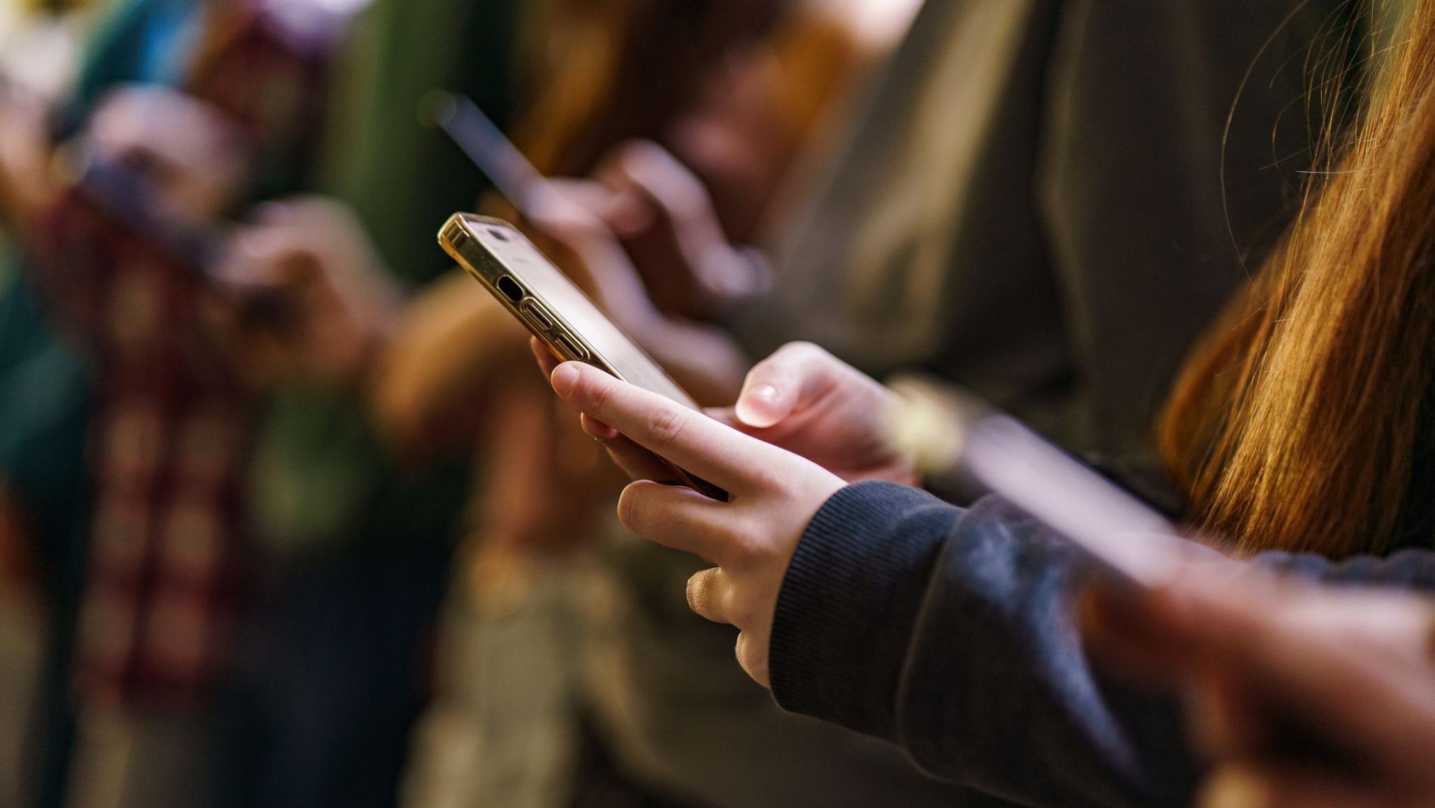 Um grupo de jovens olhando para seus smartphones.