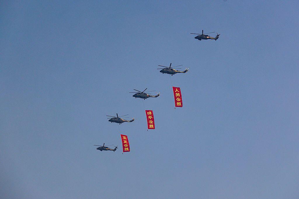 直升機在北京天安門廣場上空飛過，掛着的旗幟分別寫着「人民必勝」、「和平必勝」、「正義必勝」。