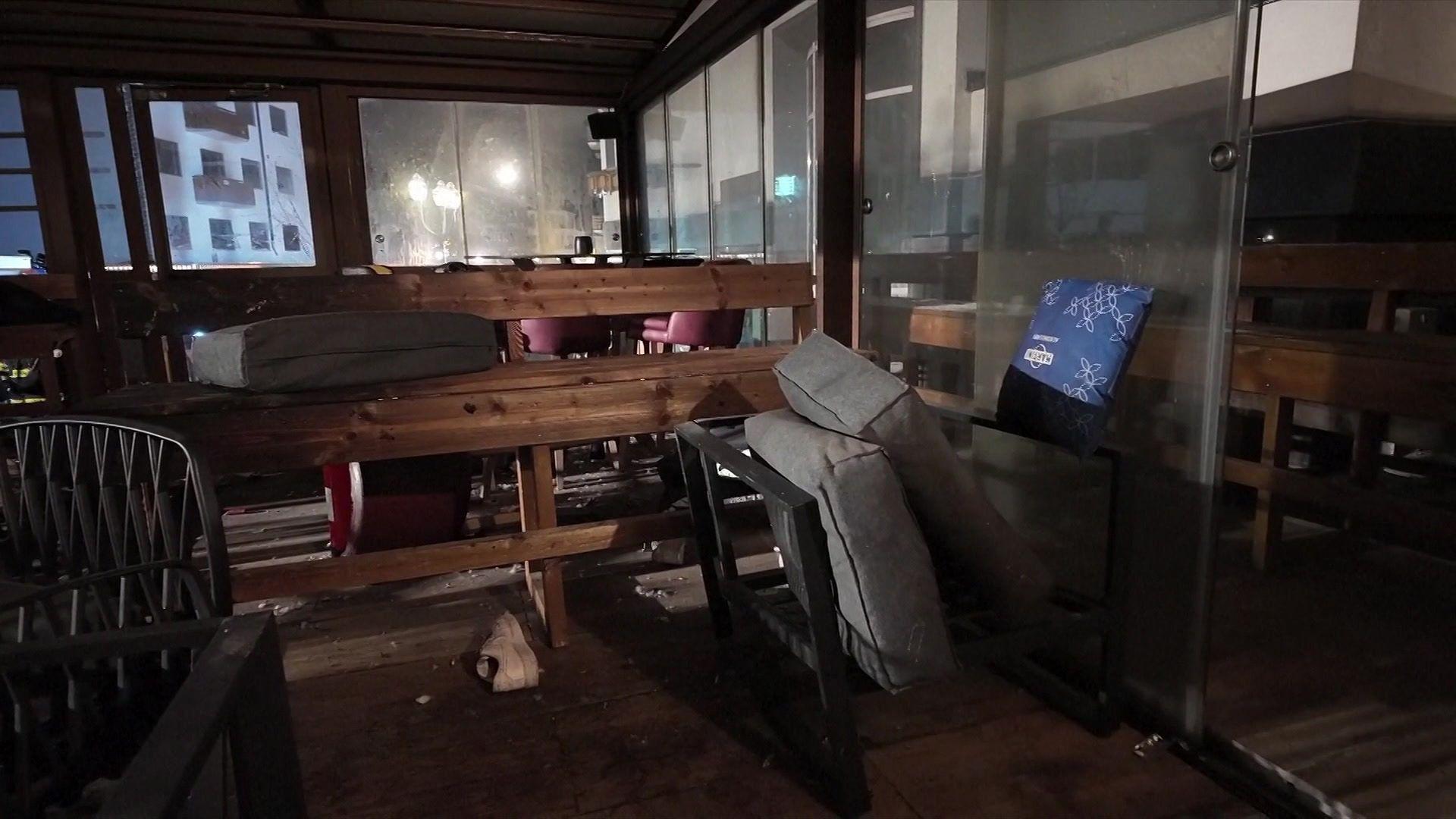 El interior oscuro de un bar muestra mesas y asientos tirados