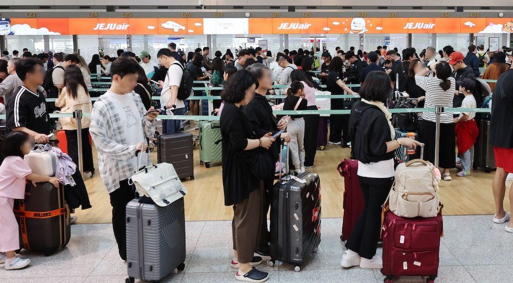 캐리어를 앞에 놓고 출국장에 들어서기 위해 줄을 서 있는 사람들