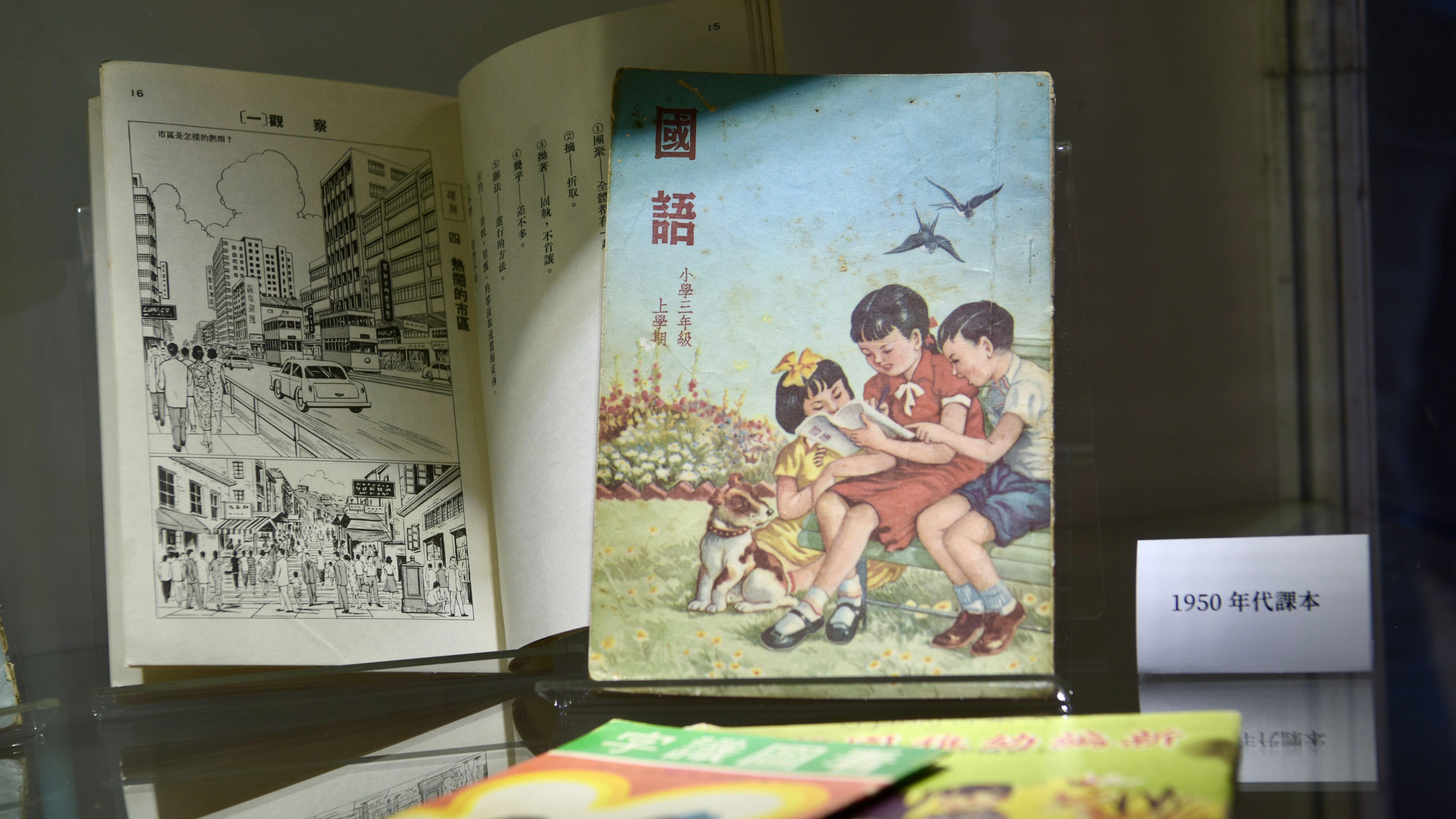 香港書展上展出的一批1950年代小三中文課本，封面為三名孩童圍著讀書，內頁為當時香港街景繪畫插圖（中新社資料圖片）