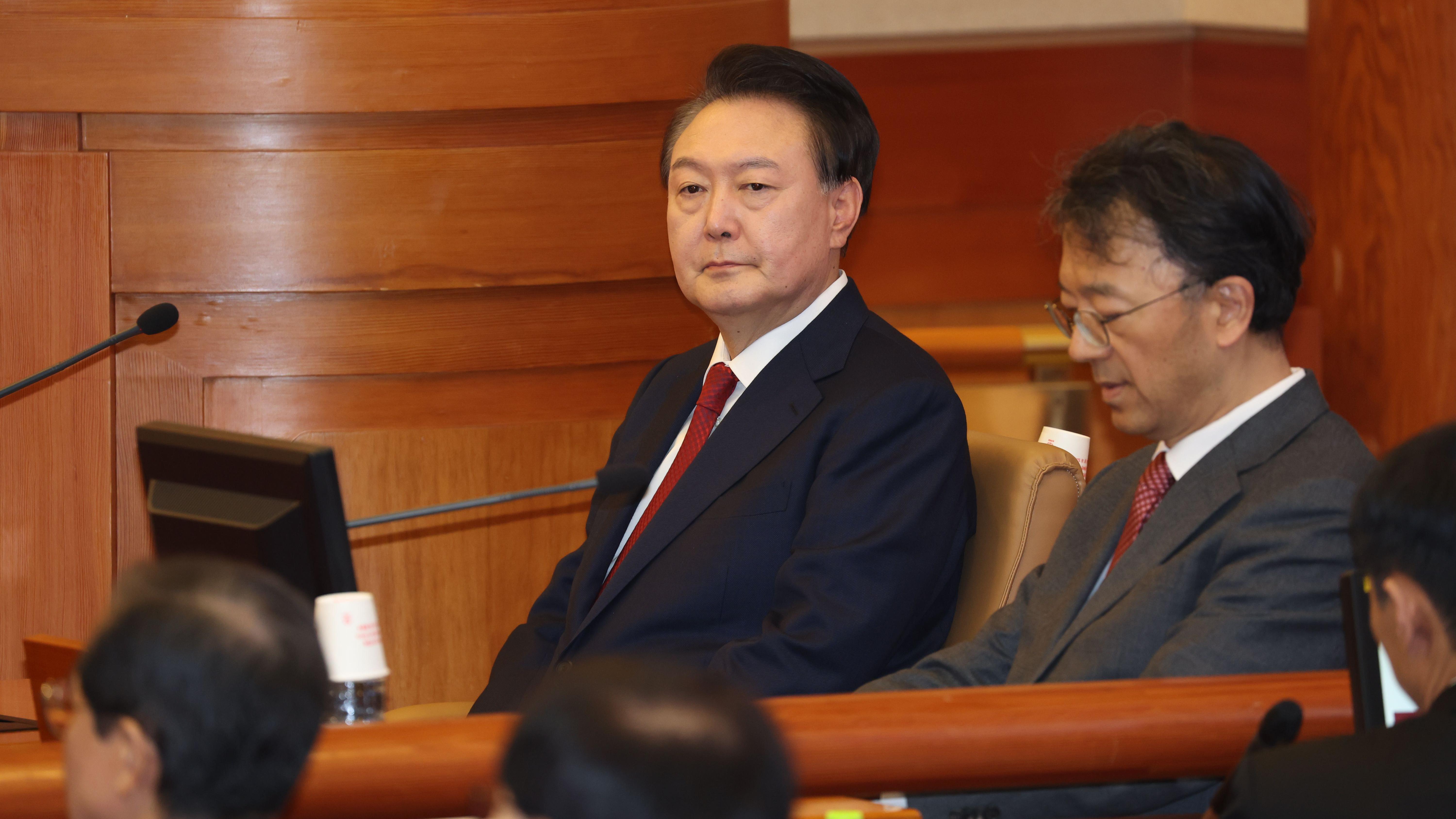 身穿黑色外套,結紅色領帶的韓國總統尹錫悅(左)在首爾韓國憲法法院就戒嚴事件彈劾案受審(21/1/2025)