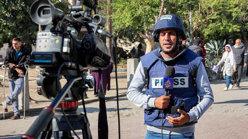 الصحفي محمد قريقع يمسك مايكروفون قناة الجزيرة أمام كاميرا
