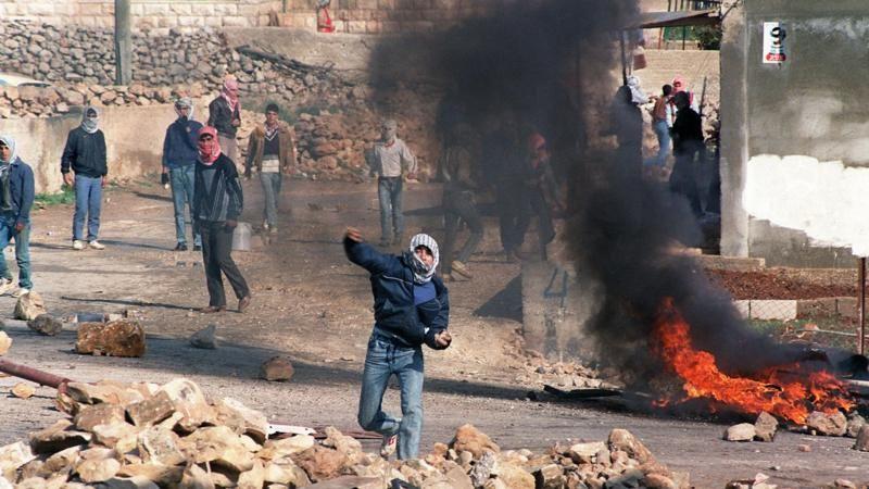 الكوفية الفلسطينية: حكاية رمز، وتاريخ شعب 4 متظاهرون فلسطينيون يلقون الحجارة على شرطة مكافحة الشغب الإسرائيلية شمال القدس، في 21 ديسمبر/ كانون الأول 1987.