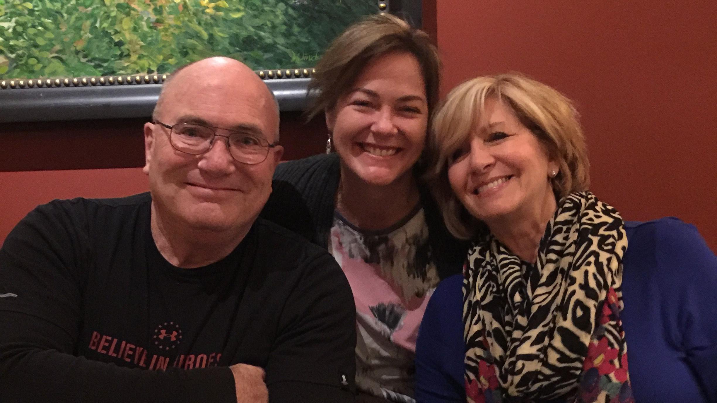 Kevin, Deb e Val sorriem à mesa de um restaurante