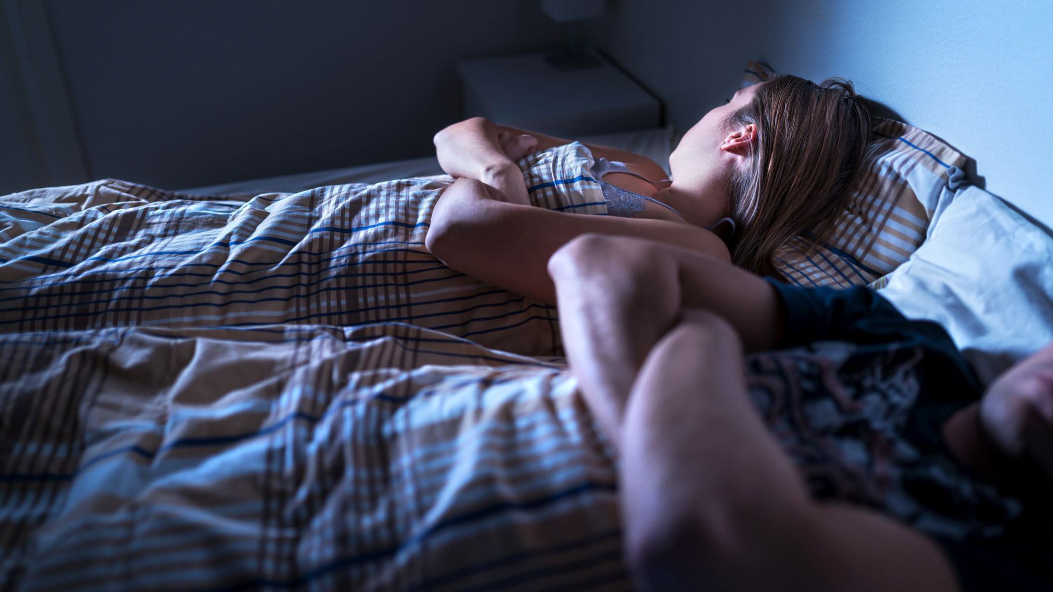 Parejas en una cama, cada uno con los brazos cruzados