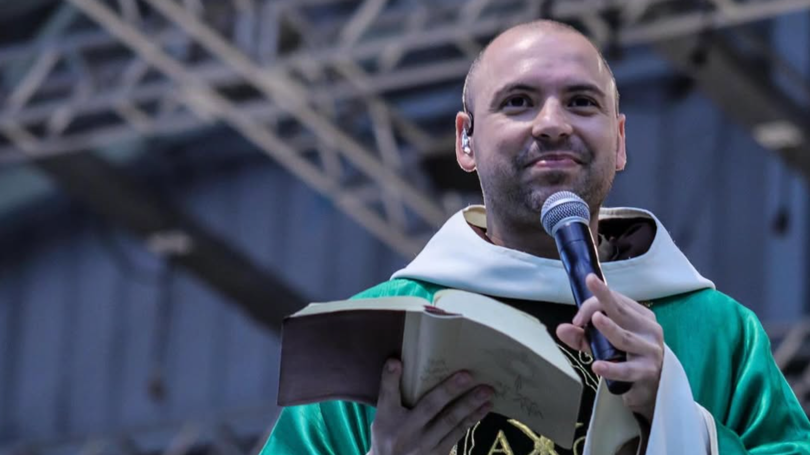 Frei Gilson segurando uma bíblia aberta e um microfone