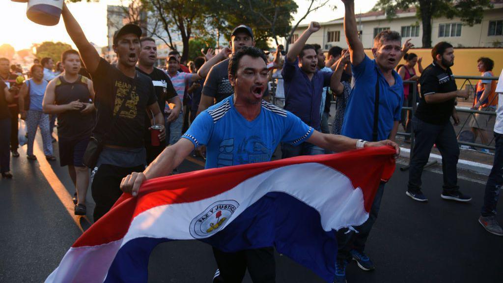 Un hombre con una bandera de Paraguay en una protesta de agricultores.