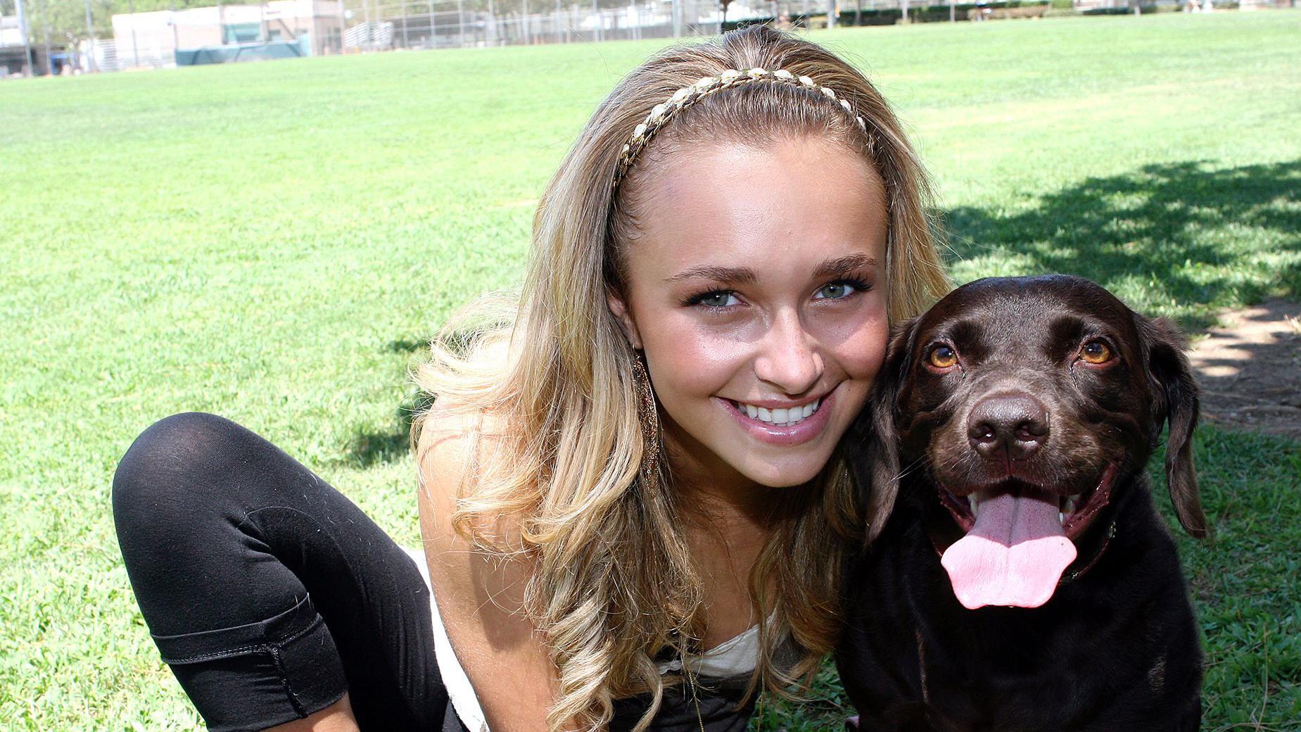 Hayden Panettiere, usando uma faixa na cabe&ccedil;a e sorrindo, posa para um retrato com seu cachorro em 2006.