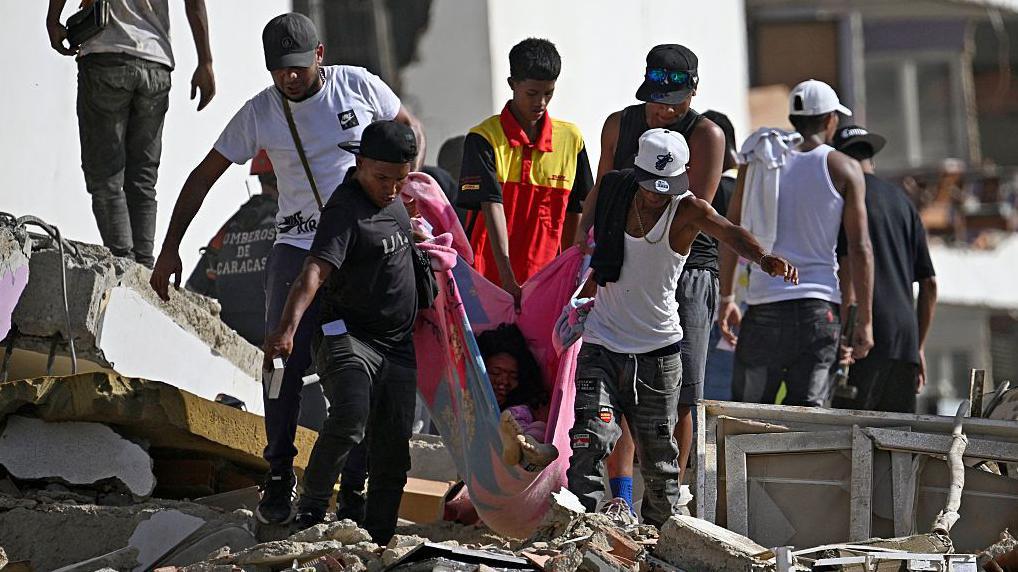 Un grupo de personas traslada a una mujer en una manta entre los escombros de un edificio de apartamentos dañado tras un terremoto en Catia La Mar, estado de La Guaira, Venezuela.