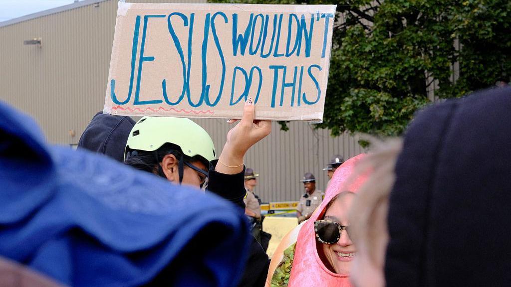 Manifestante segura um cartaz com os dizeres 
