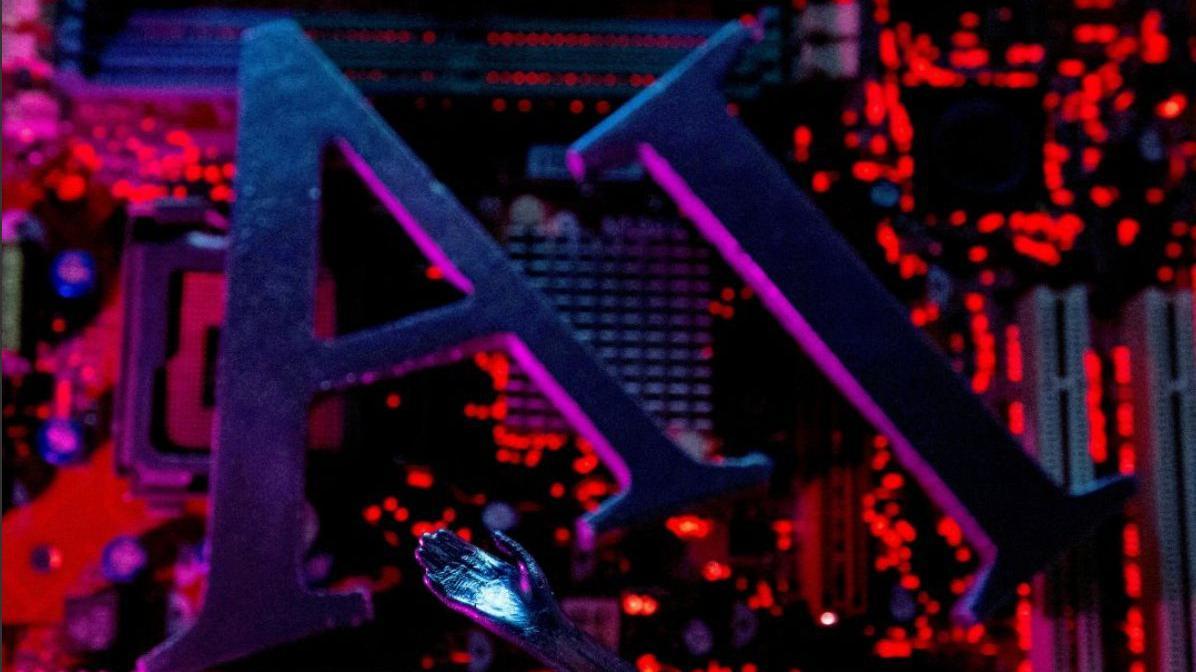 صورة توضيحية، تحوي حروف "الذكاء الاصطناعي" ويد روبوت موضوعة على لوحة أم لجهاز كمبيوتر