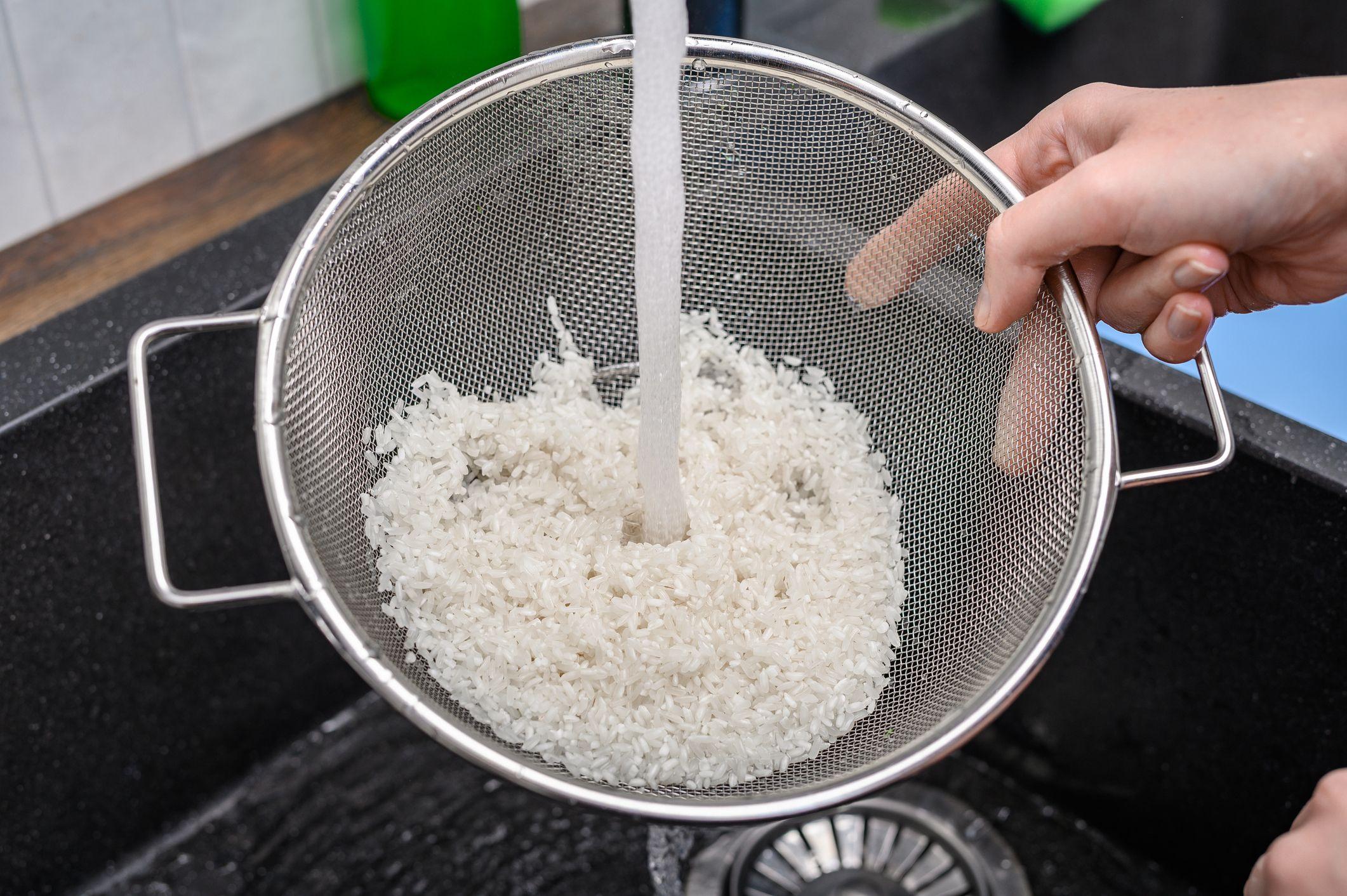 Una persona enjuaga el arroz en un colador.