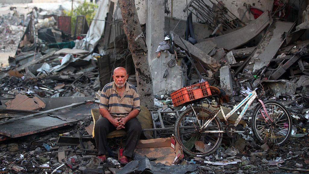 Un palestino descansa entre los escombros en el lugar donde un ataque israelí impactó una casa en la Ciudad de Gaza, el 30 de julio de 2026. 