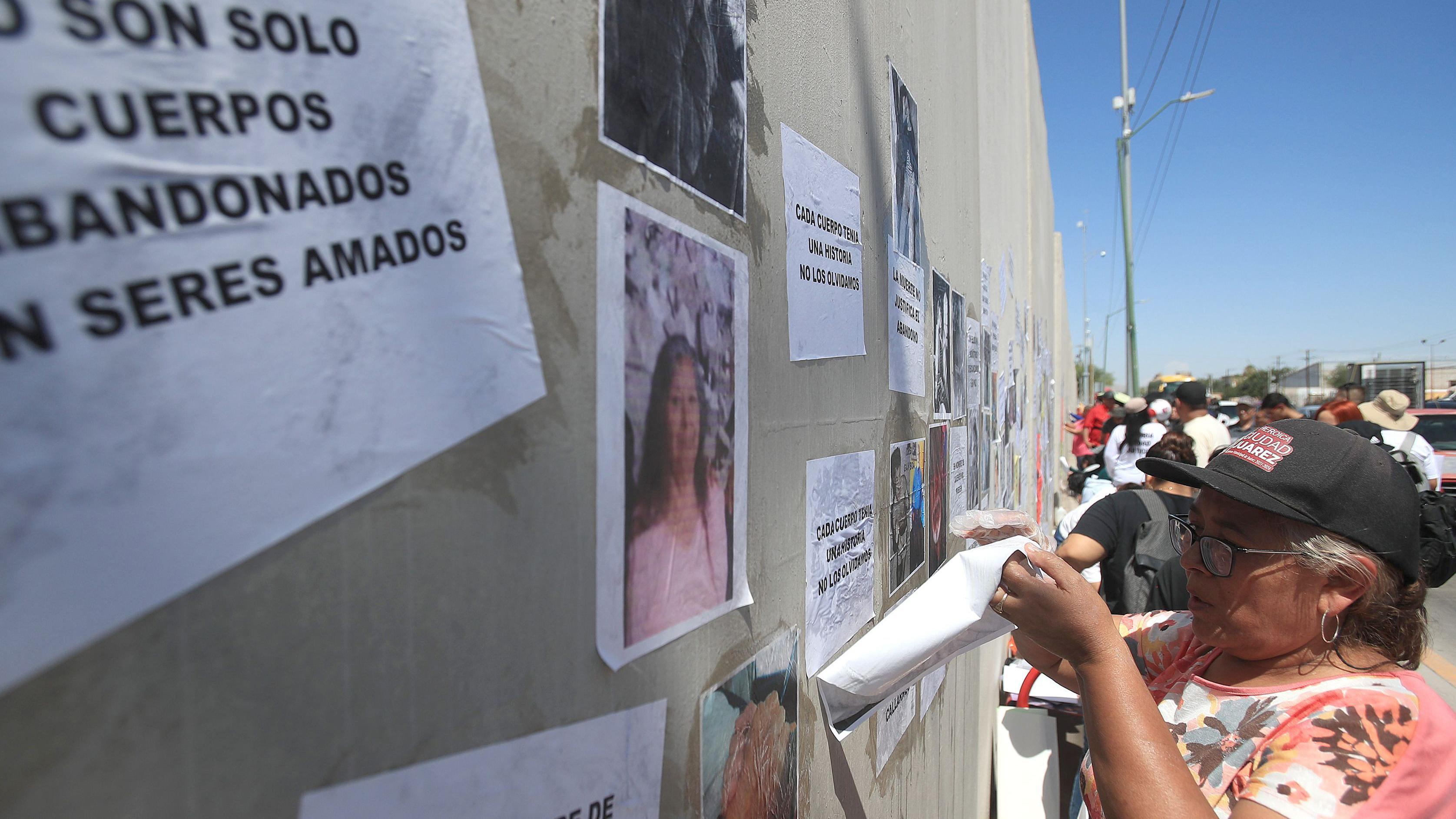 Personas participan en una protesta frente a la Fiscalía General del Estado en Ciudad Juárez, México, el 2 de agosto de 2025. Los cuerpos de sus familiares fueron encontrados apilados en un crematorio de Ciudad Juárez, en la frontera al norte de México, protestaron para exigir justicia y transparencia en las investigaciones.
En la imagen se ve a una mujer con una camisa de estampado de flores pegar un cartel en un muro.