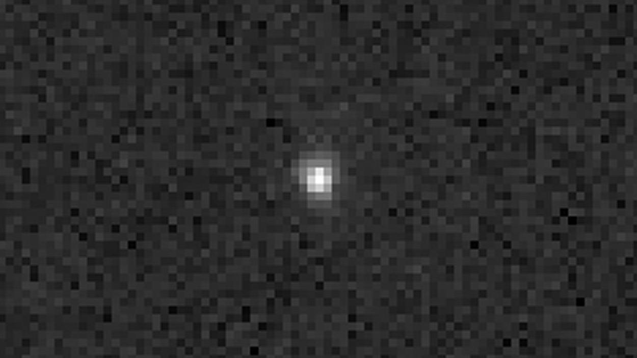 Un grupo de píxeles blancos forma un punto blanco en el centro de la imagen sobre un fondo negro y gris muy pixelado.