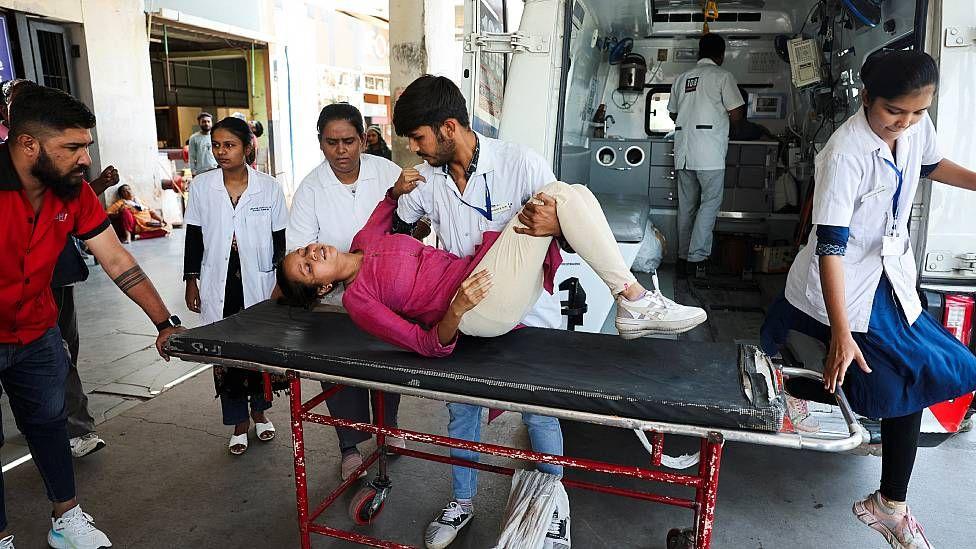 Una joven en una camilla junto a la ambulancia es ayudad por paramédicos tras desmayarse debido al calor intenso en Ahmedabad, en India