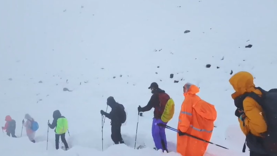 Senderistas ataviados en ropas invernales de diferentes colores descienden por un sendero cubierto de nieve.