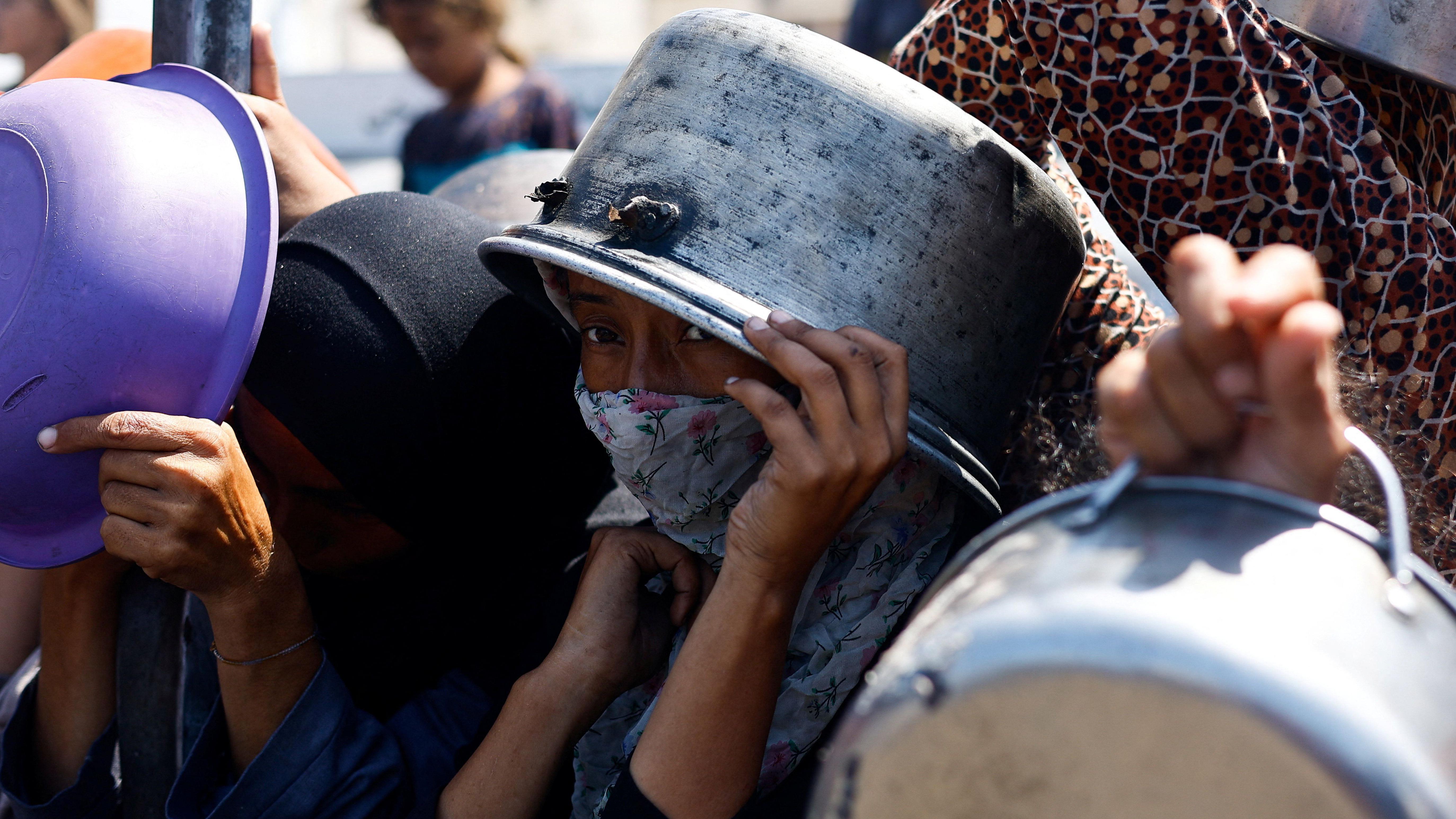 يحمل شخص وعاء على رأسه بينما ينتظر للحصول على طعام في مدينة غزة في 28 أغسطس/ آب 2025