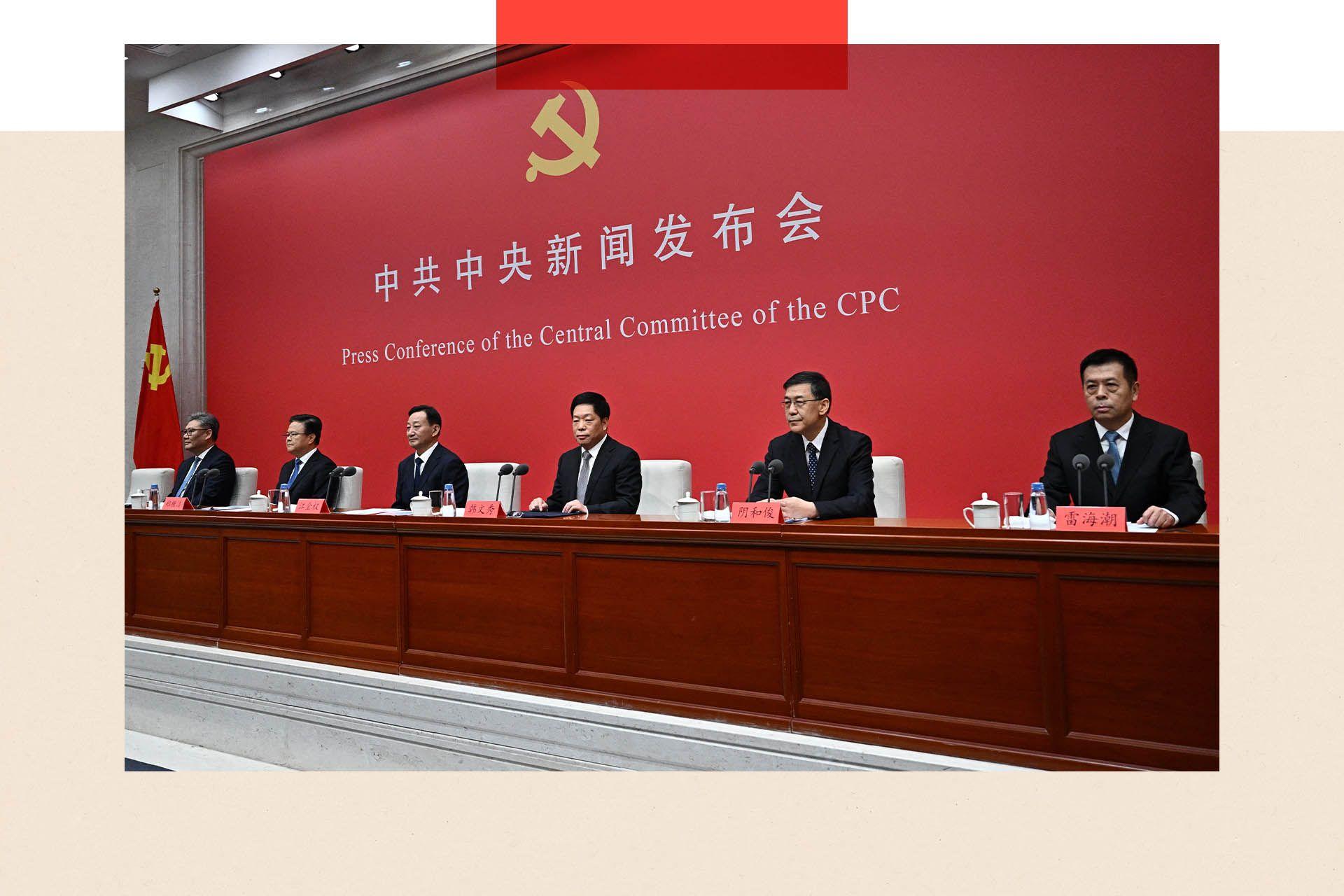 Members of the CCP sit at a table in front of a red background.
