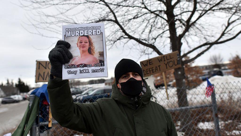 Un manifestante sostiene un cartel con una foto de Renee Nicole Good, quien fue disparada y asesinada el 7 de enero por un agente federal, durante una manifestación frente al Edificio Federal Bishop Whipple en Minneapolis, Minnesota, el 15 de enero de 2026. (Foto de Octavio JONES / AFP vía Getty Images)