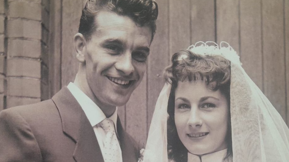 A black and white wedding photo of a young couple. The man has 