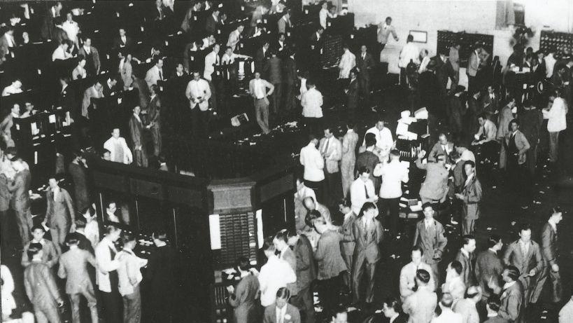 Varias decenas de comisionistas de bolsa están parados con expresión de preocupación.