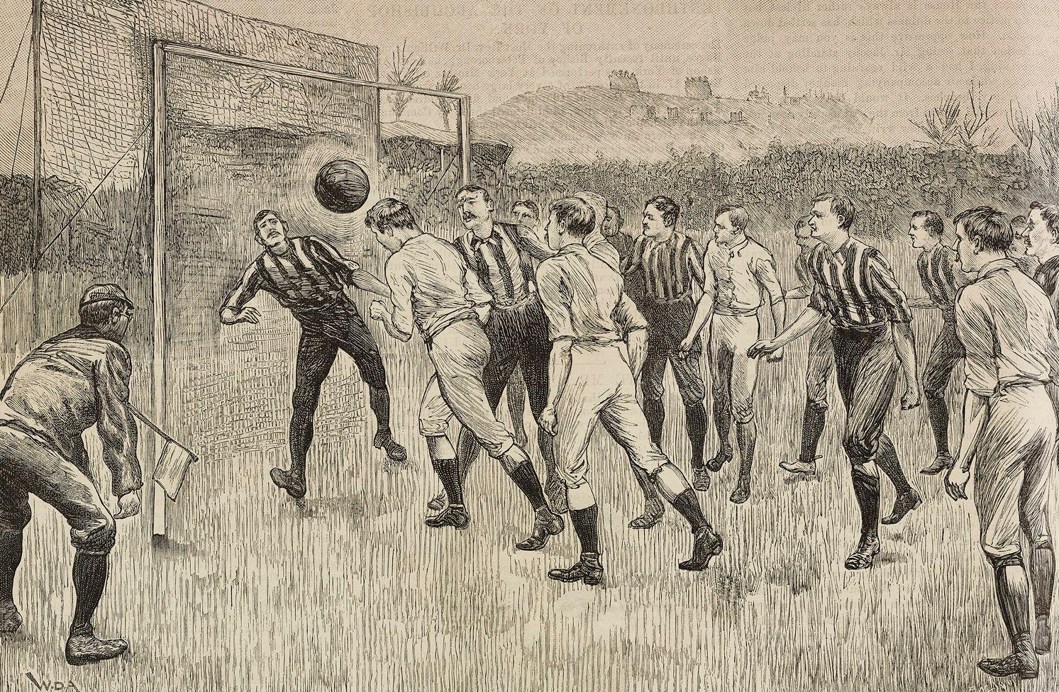 Hombres con pantalones hasta debajo de la rodilla, medias altas y camisas de rayas verticales, unos, y camisas blancas, otros, en un campo de fútbol. Un jugador frente a la portería cabecea el balón y el arquero está atento. Un árbitro con una gorra y un banderín está atento a la jugada 