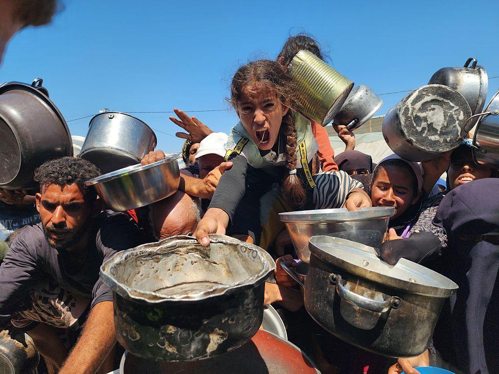 Palestinos, incluidos niños, se agolpan para recibir comida distribuida por organizaciones de ayuda en la ciudad de Gaza el 26 de julio de 2025.
