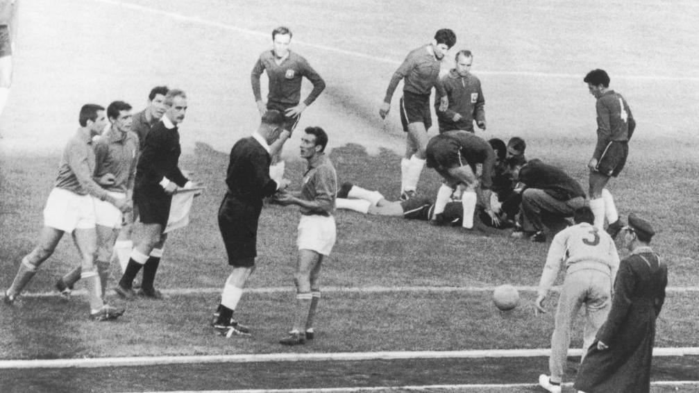 Referí rodeado de jugadores en una imagen en blanco y negro.