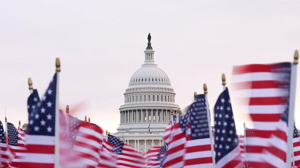Imagen del Capitolio de los Estados Unidos con banderas del país tomada durante la mañana después de que el Senado aprobara la legislación para reabrir el gobierno federal.