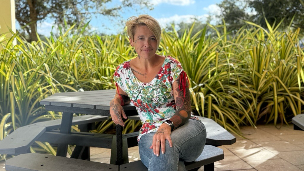 Chantille Manuel sentada en un banco de madera en un jardín.