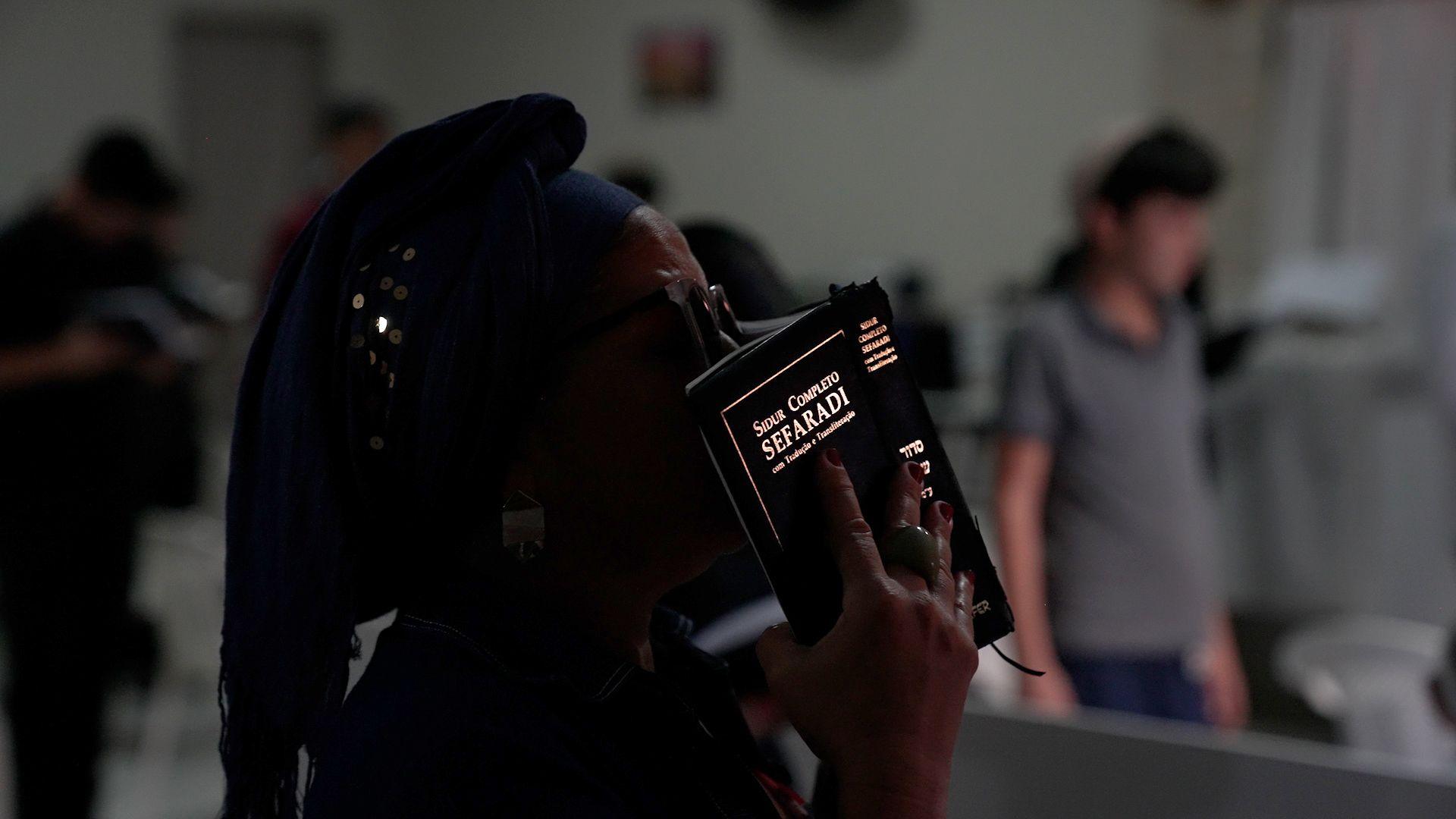 Mulher com lenço na cabeça e livro religioso