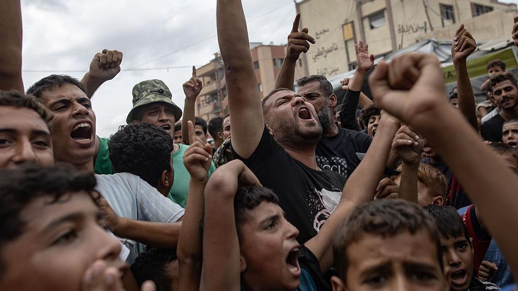 Crian&ccedil;as, adolescentes e adultos em Gaza, com os bra&ccedil;os para o alto, comemoram o an&uacute;ncio do cessar-fogo