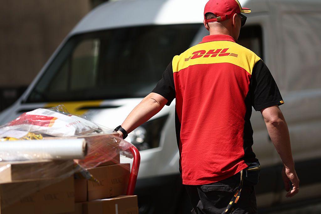 Un trabajador de DHL empujando un carrito con paquetes